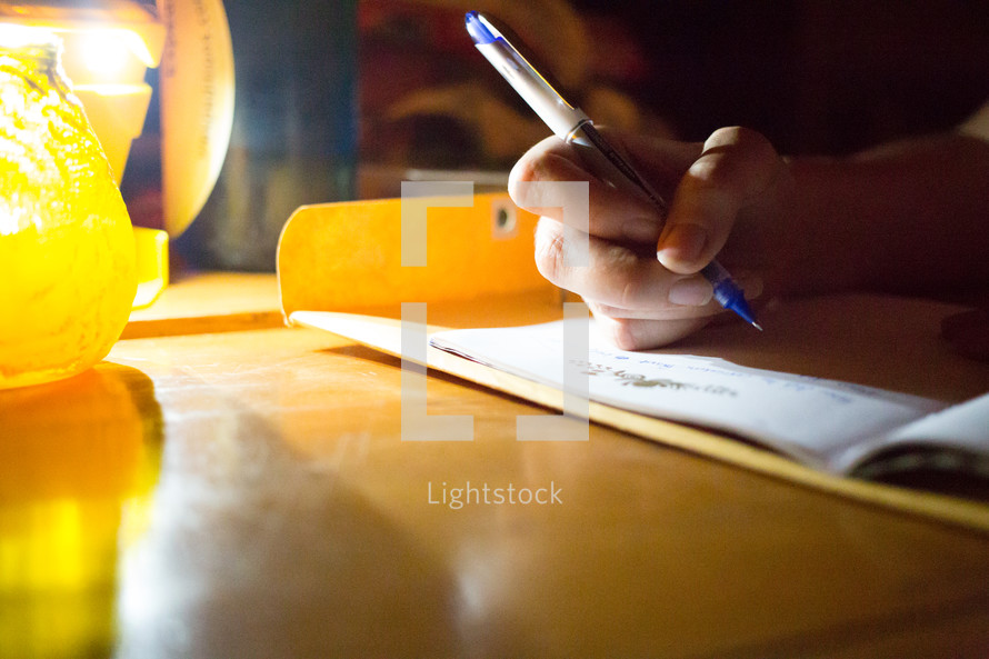 a child doing homework using a flashlight to light his workspace 