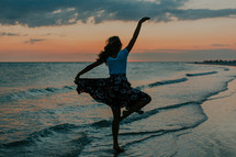 a woman dancing on a beach 