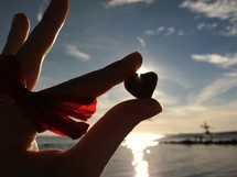 hand holding up a heart shaped rock 