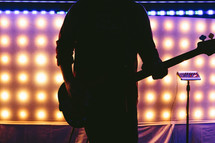 silhouette of a man playing a guitar on stage 