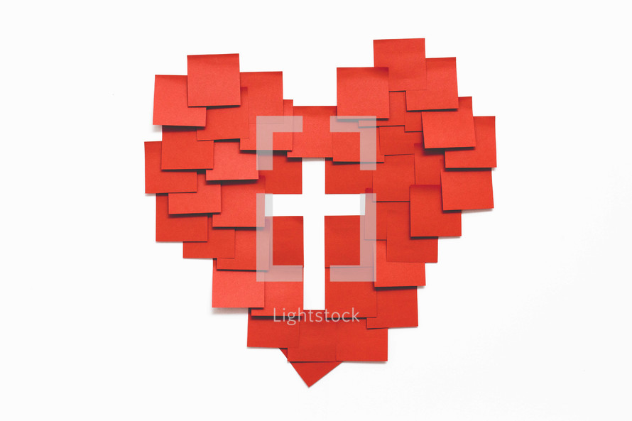 A red heart and a white cross made with squares of paper on a white background.