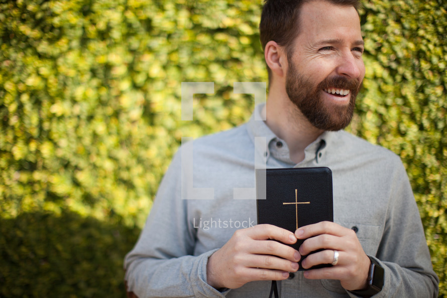 a smiling man holding a Bible 