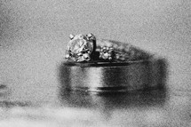 Engagement ring and wedding band sittng on top of solid surface.