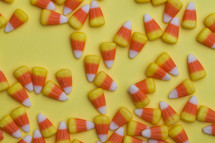 scattered candy corn on a yellow background 