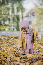 toddler playing in fall leaves 