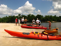 Friends with kayaks on the shore of a river.
