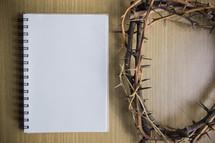 blank notepad and crown of thorns on a wood background 
