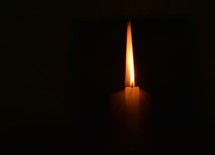A candle burning in darkness. 