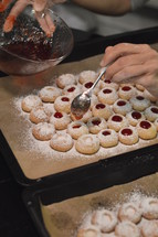 baking Christmas cookies and filling warm liquid jam into them