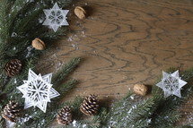 star ornaments, pine cones, snow, and pine boughs on a wooden  background 