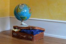 a globe on a packed suitcase 