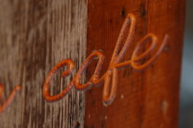 A sign reading "cafe" against rustic boards.