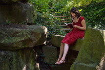 woman sitting in a forest reading a Bible 