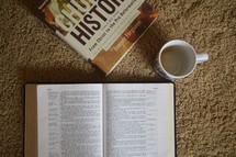 open Bible and Church history book with a coffee mug 