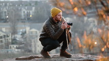 a man squatting holding a camera 