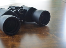 binoculars on wood table 