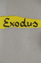 torn open kraft paper over yellow paper with the name of the book Exodus