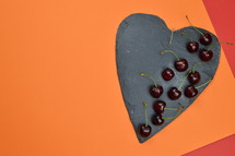 cherry on a heart shape piece of slate and colored paper 