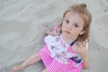 a little girl sitting in the sand 