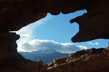 view of mountains through an opening in red rock 