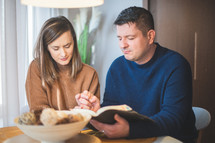 husband and wife reading a Bible together holding hands 