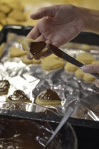 Woman spreading liquid chocolate onto the marzipan layer of Christmas cookies
