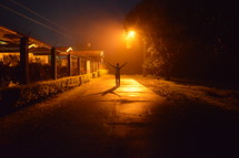 a man with raised arms standing on a sidewalk at night 