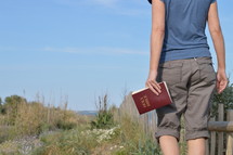 woman walking with Bible in hand in the dunes near the beach