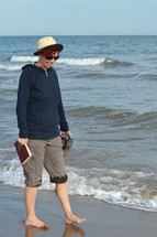 woman walking on a beach carrying a Bible 
