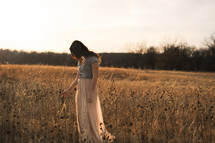 a woman walking in a field of dried wildflowers 