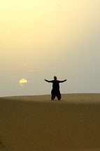man dancing in front of the setting sun in a desert in India 