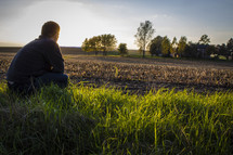 man sitting in a freshly plowed field 