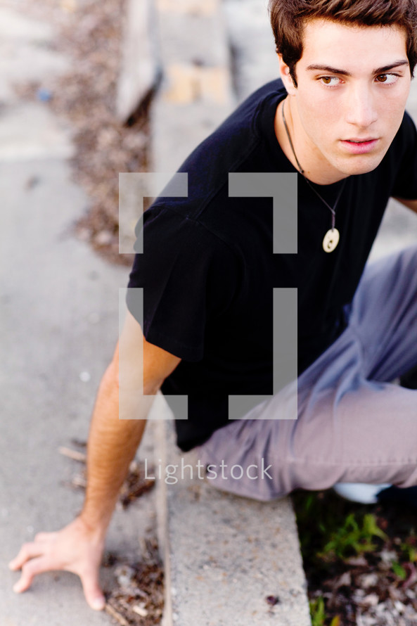 teen young man  sitting on a curb model fashion