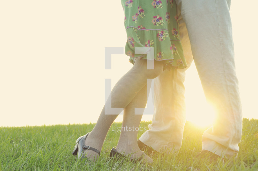 Couples legs and shoes standing in grass