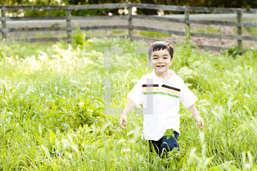 boy child playing in tall green grass field