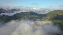 Aerial panoramic view above mist clouds in magic country landscape at morning sunrise
