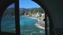 view of waves crashing into cliffs through a window along the coast of Italy 