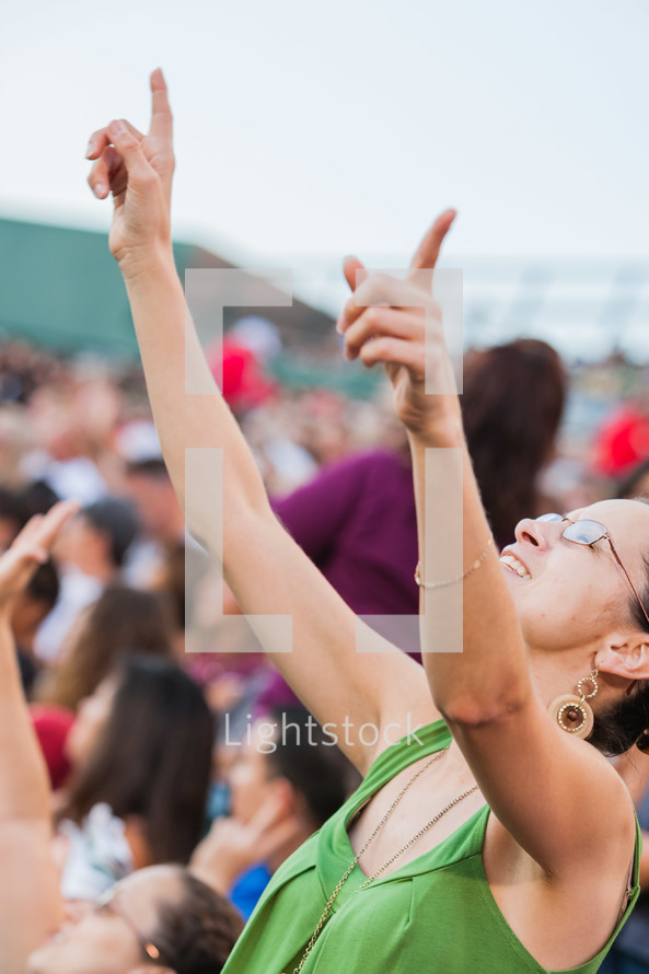 A woman with hands raised point toward sky in worship 