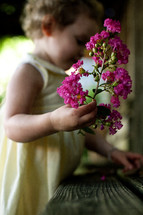 toddler girl holding branch of flowers