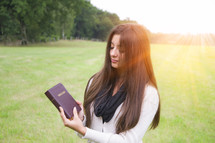 a woman holding a Bible outdoors 