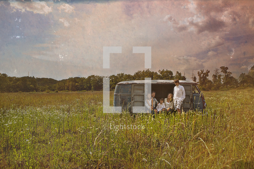 family sitting in an old van in a field