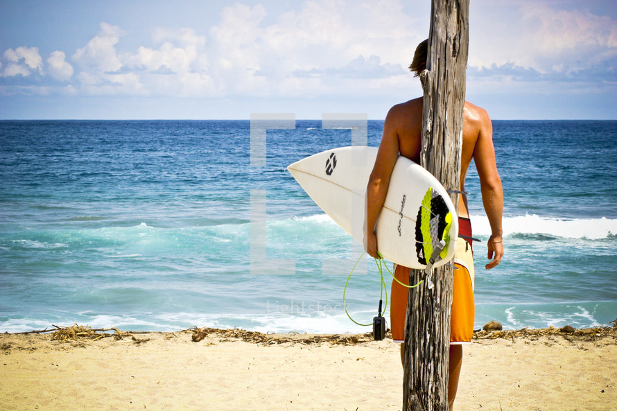 surfer holding a surfboard in front of ice blue water