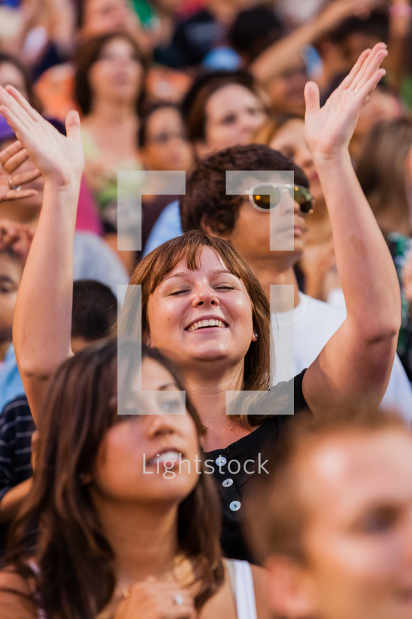 Church service woman raising hands in worship eyes closed crusade