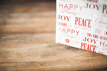 A Christmas present on a wood table - Peace and joy - wrapping paper