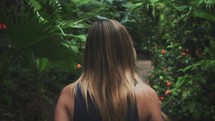 a woman walking through botanical gardens 