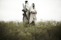 pregnant Mary and Joseph standing back to back in a field