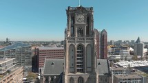 Aerial drone footage rising along the face of a church tower, revealing the city of Rotterdam, Netherlands.