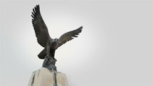 Eagle with the cross in its beak - bronze statue. Memorial Day concept.