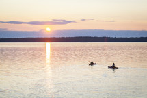 paddling kayaks on a boat at sunset 