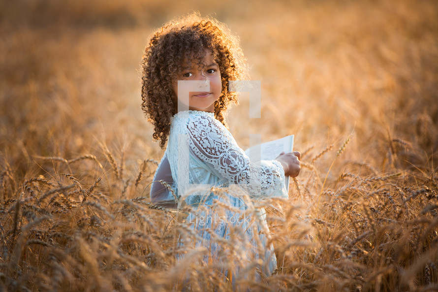 a little girl in a field of wheat 